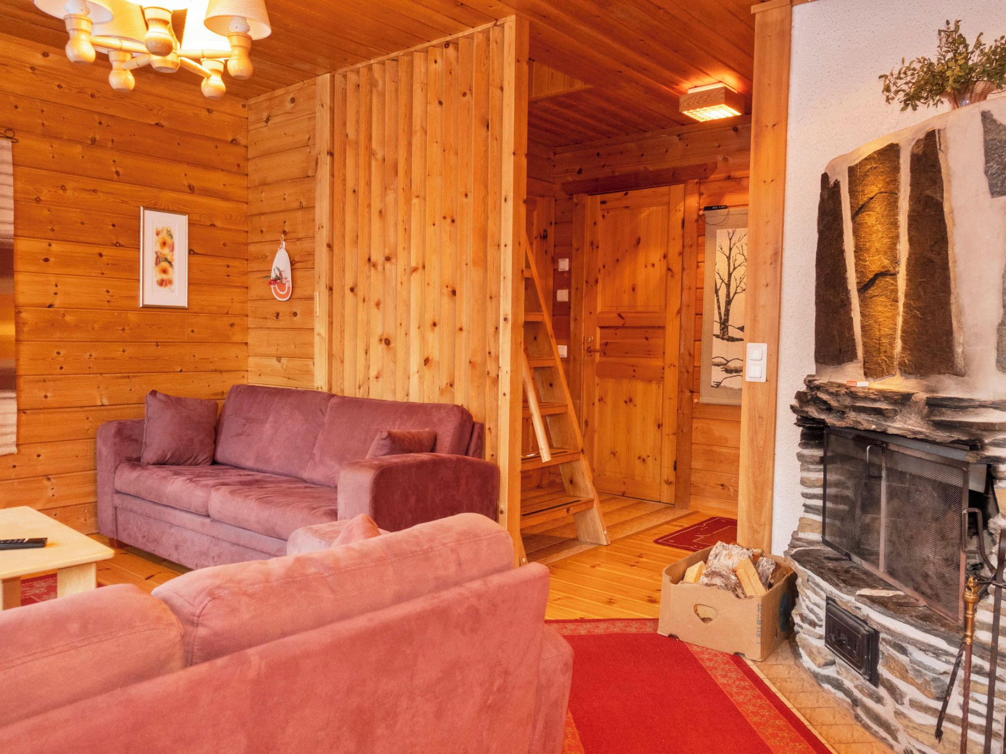 A wooden interior with a fireplace, a sofa, and a ladder.
