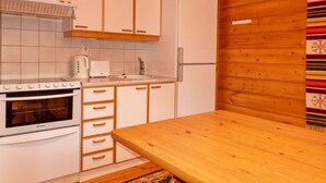 A compact kitchen with white cabinets, a built-in oven, a microwave, and a sink. - Susitupa 6 by Interhome (Salla)