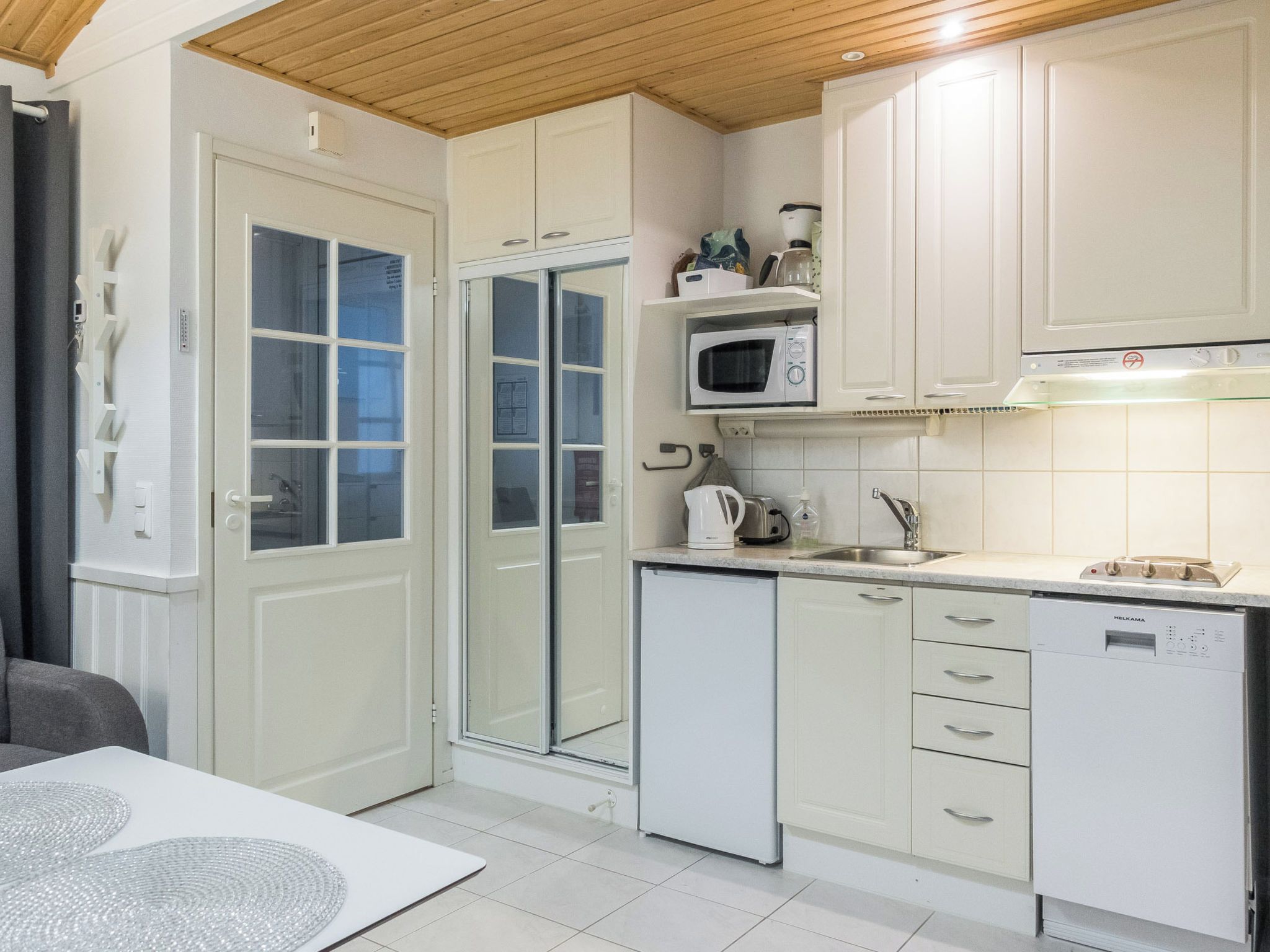 A compact kitchen with white cabinetry, a microwave, a coffee maker, and a dishwasher.