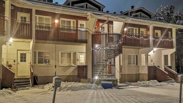 A multi-story building with balconies, a snow-covered ground, and a visible mailbox.