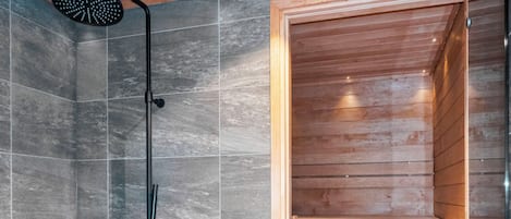 A shower area with a wooden bench and a metal bucket.