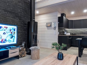 A modern living room with a fireplace, a television, and a dining area.