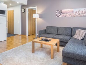 Ein modernes Wohnzimmer mit einem grauen Sofa, einem Holztisch und einem weißen Teppich.