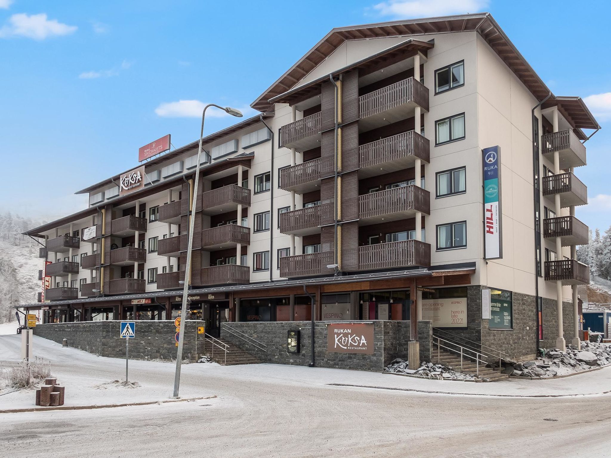 A multi-story hotel with balconies, a restaurant, and a ski lift sign.