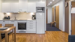 A compact kitchen with white cabinets, a built-in oven, a refrigerator, and a coffee maker. - Ruka ski chalets 64, 1302 by Interhome (Kuusamo)