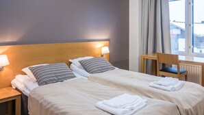 A hotel room with two beds, each with a headboard, bedside lamps, and a view of the outside through a window. - Ruka ski chalets 64, 1302 by Interhome (Kuusamo)