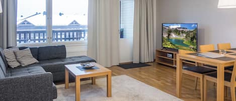 Ein modernes Wohnzimmer mit Sofa, Couchtisch, Fernseher und Essbereich.