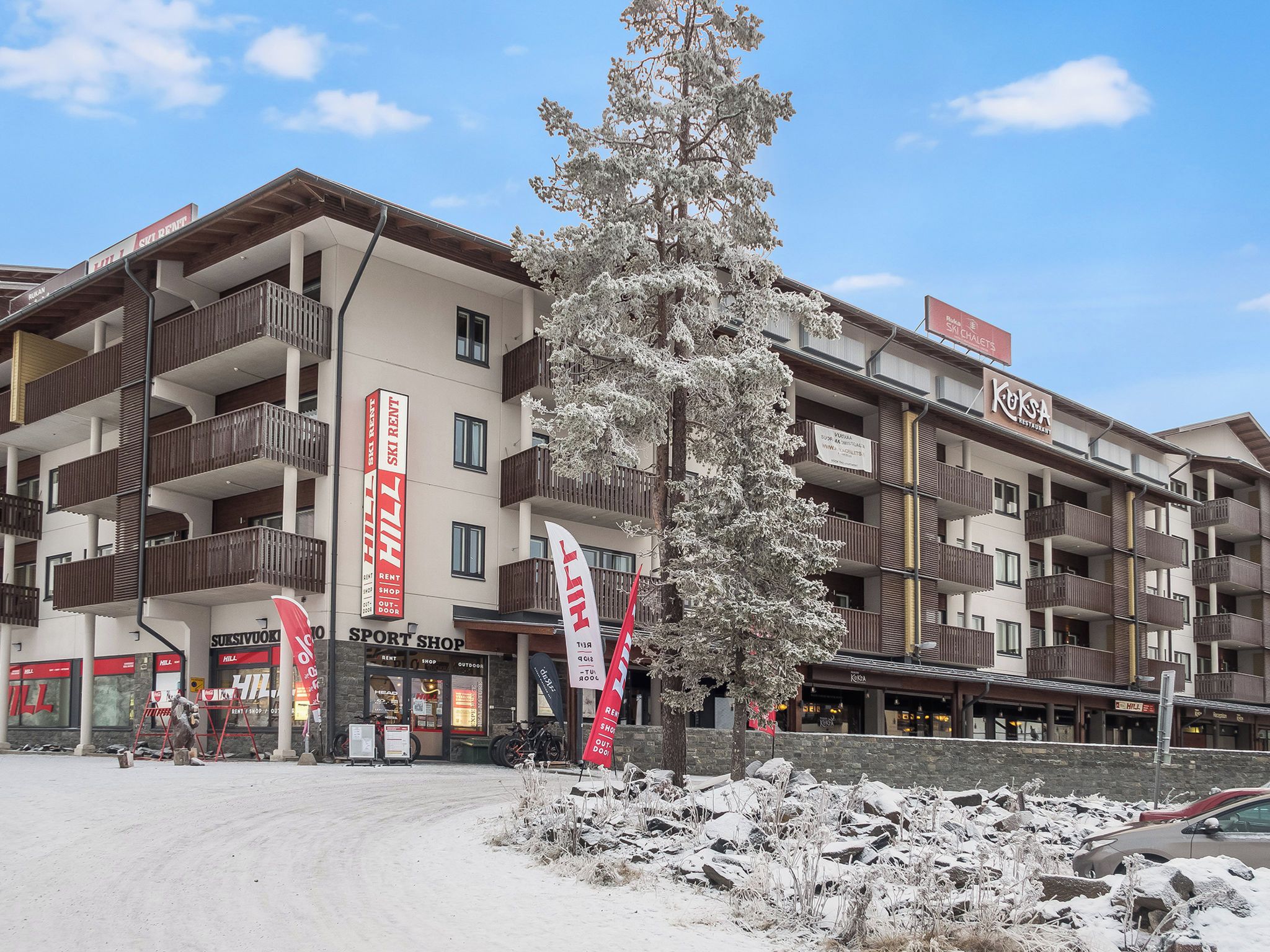 Un hôtel à plusieurs étages doté de balcons, d’un magasin de location de matériel de ski et d’un restaurant.