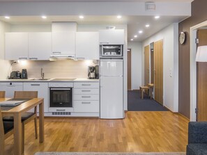 Eine kompakte Küche mit weißen Schränken, einem eingebauten Ofen, einer Mikrowelle und einem Kühlschrank.