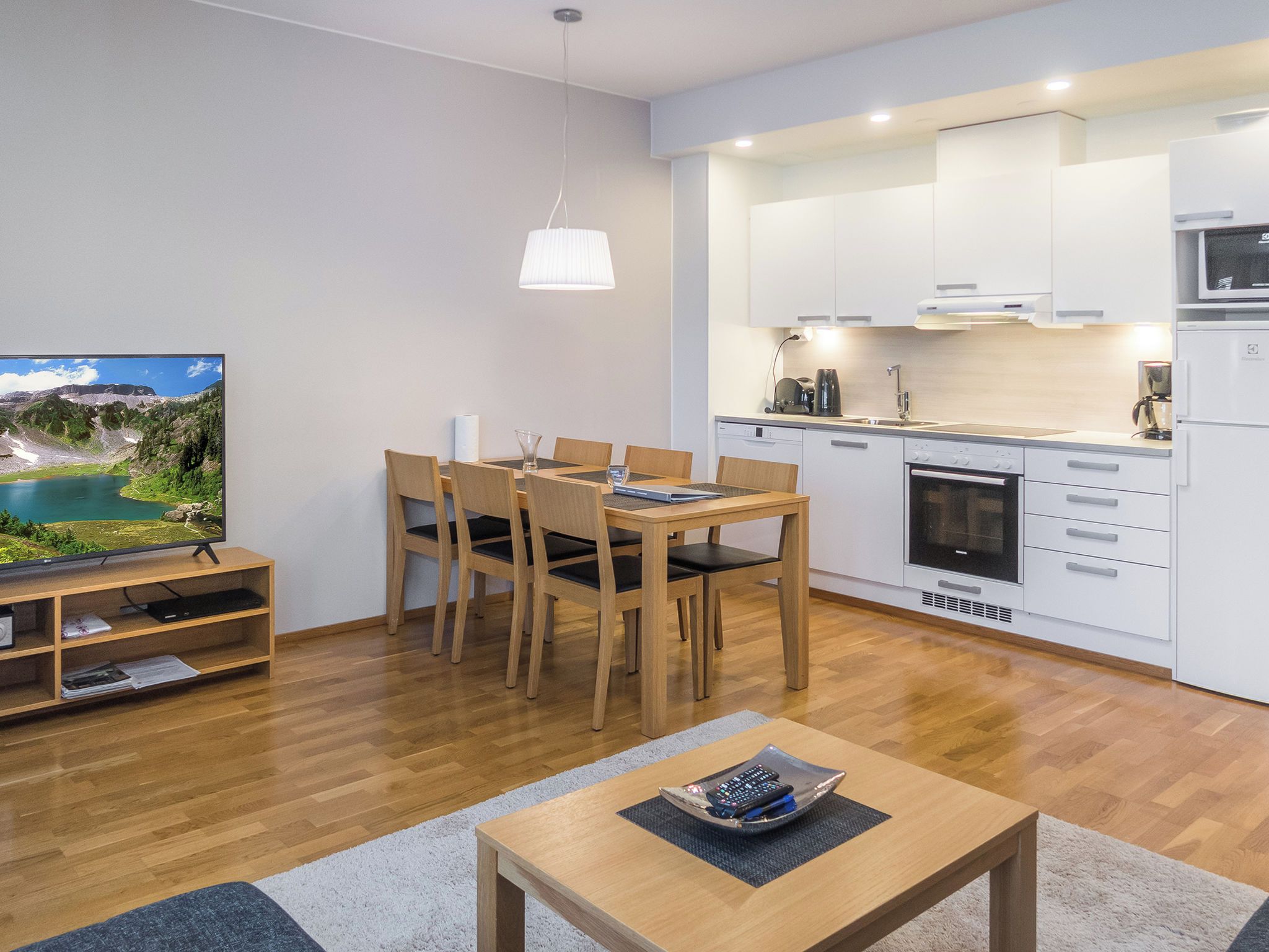A modern kitchen with white cabinets, a built-in oven, and a microwave.