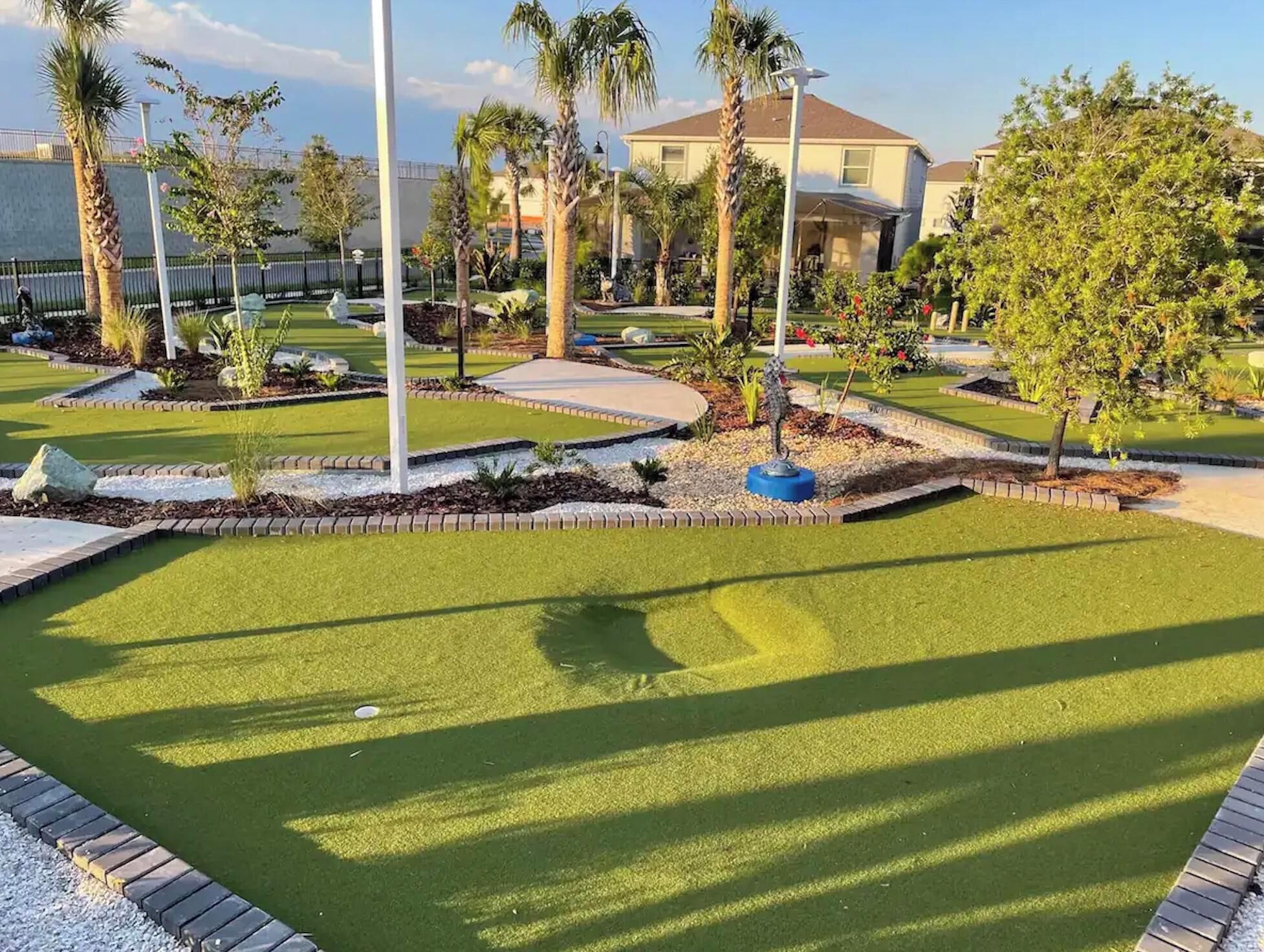 A well-maintained golf course with manicured lawns, palm trees, and a clear sky.