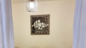 A bedroom with a bed, two pillows, a wall-mounted artwork, and a hanging light fixture. - Coeur de ville, T2, pedestrian street, Digne les Bains  (Digne-les-Bains)