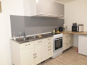 Een keuken met een spoelbak, fornuis, oven, magnetron en kastjes.
