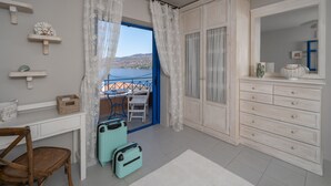 Una habitación con escritorio, silla, armario, cómoda y vista al mar.