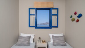 Un dormitorio con dos camas, una ventana con contraventanas azules y vistas a un paisaje lejano.