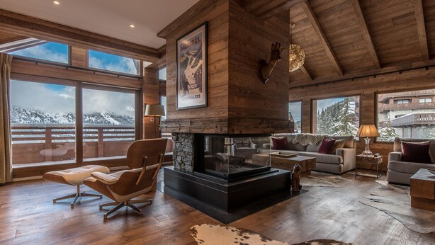 A spacious living room with a fireplace, wooden beams, large windows, and a view of a snowy mountain. - Luxurious Ski-in/Ski-out Apartment with Jacuzzi and Private Hammam (Méribel)
