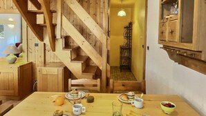 A wooden interior with a staircase, a dining table with food and drinks, and a small kitchen area.