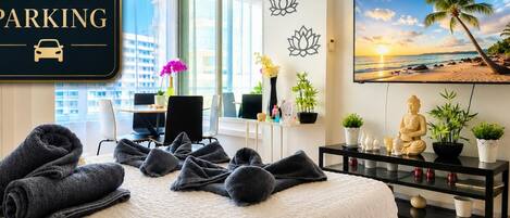 Habitación de hotel con cama, escritorio, silla, televisión y un letrero que indica estacionamiento privado gratuito.