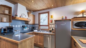 Une cuisine moderne avec des meubles en bois, un lave-vaisselle encastré et un réfrigérateur en acier inoxydable.