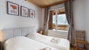 Une chambre d’hôtel avec deux lits, un plafond en bois, une fenêtre avec des rideaux et des œuvres d’art encadrées accrochées au mur.