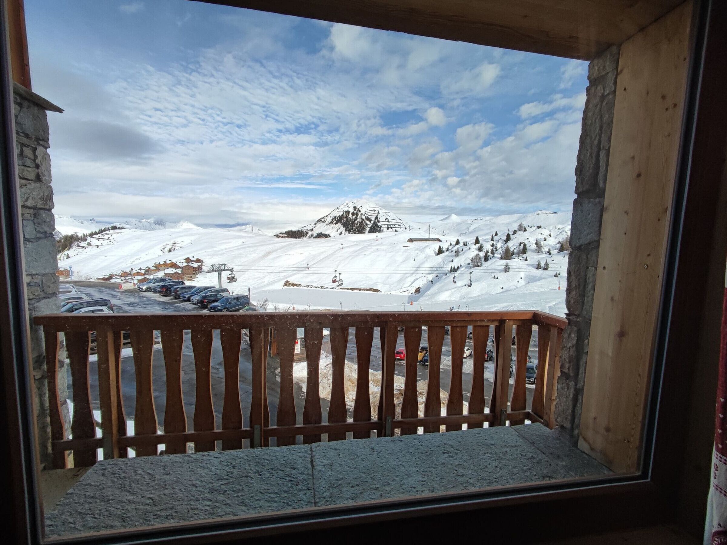 A balcony with a view of a snowy mountain landscape, including a ski lift and a mountain peak.