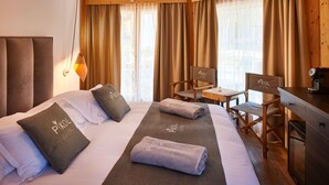 A hotel room with a bed, a desk, and a chair. There are towels on the bed and a sign on the wall.