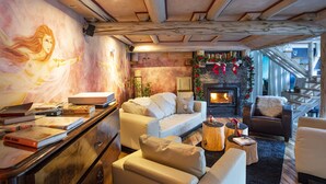A cozy living room with a fireplace, books, and a staircase leading to an upper level.