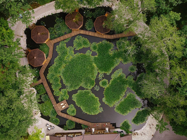 Vista aérea de un resort con estructuras hexagonales, una masa de agua central y follaje circundante.