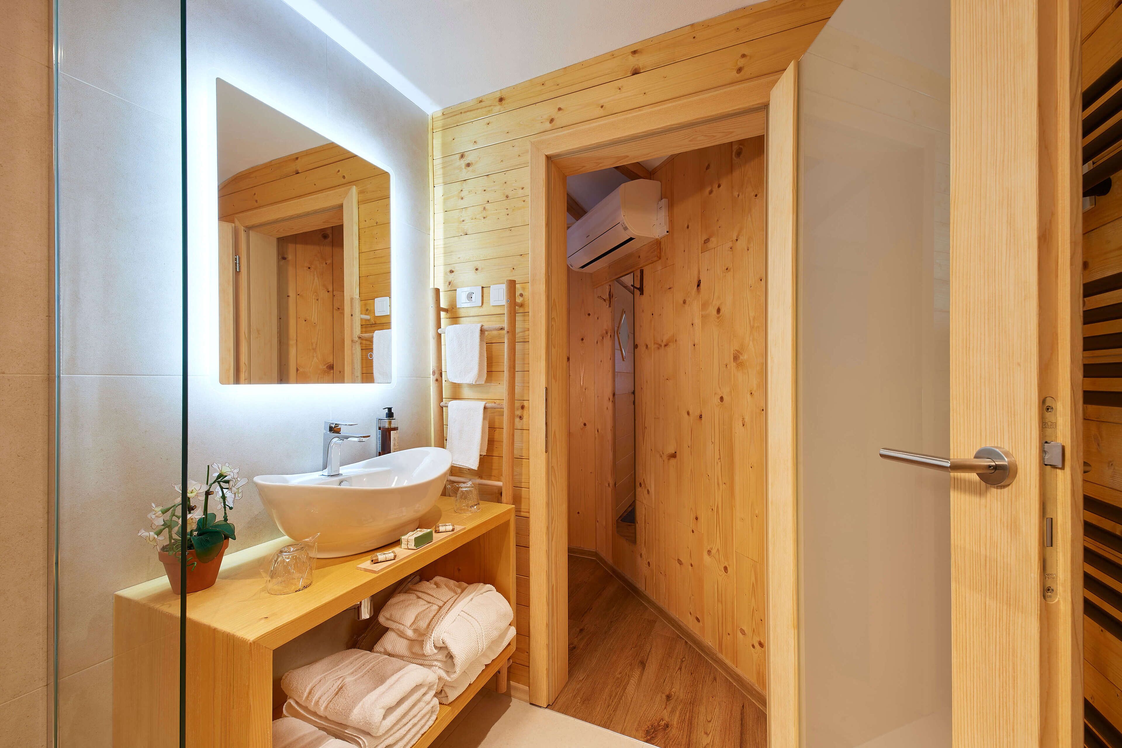 Une salle de bain moderne avec un intérieur en bois, un grand miroir, un lavabo et un porte-serviettes.