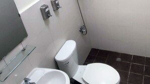 A small bathroom with a toilet, a sink, and a shower. - Ginto Residence (Coron)