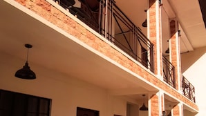 A multi-story building with a balcony on the upper floor, a door, and a staircase leading to the upper level. - Ginto Residence (Coron)
