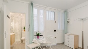 Une salle de bain moderne avec une douche à parois de verre, des toilettes et un lavabo. On y trouve une petite table avec une chaise et une plante en pot.