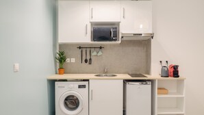 Une cuisine compacte équipée d’un lave-linge, d’un lave-vaisselle, d’un four à micro-ondes et d’un petit évier.