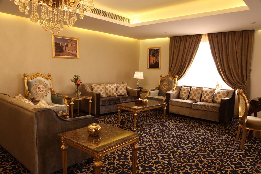 A luxurious living room with a patterned carpet, elegant furniture, and a chandelier.
