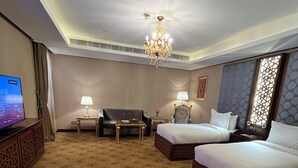 A hotel room with two beds, a sofa, a TV, and a chandelier. - AL Rahden Hotel  (Riyadh)