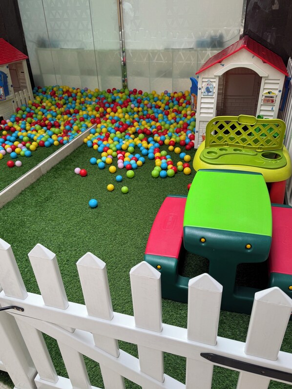 A children's play area with a ball pit, a small house, and a toy kitchen set.