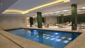 A modern indoor swimming pool with a clear water surface, surrounded by lounge chairs and a well-lit ceiling. - AL Rahden Hotel  (Riyadh)