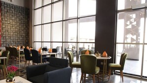 A modern dining area with multiple tables and chairs, large windows, and a decorative wall. - AL Rahden Hotel  (Riyadh)