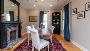 A dining room with a wooden table, white upholstered chairs, a patterned rug, a fireplace, and a bookshelf. - This house is a 3 bedroom(s), 2.5 bathrooms, located in Lexington, KY. (Lexington)