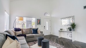 A spacious living room with a grey sectional sofa, a white door, and a decorative mirror. - 4BR w pool, dog-friendly, near Westgate (Phoenix)
