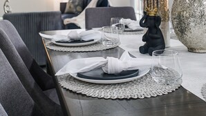A dining area with a table set for two, a decorative vase, and a television in the background. - 4BR w pool, dog-friendly, near Westgate (Phoenix)