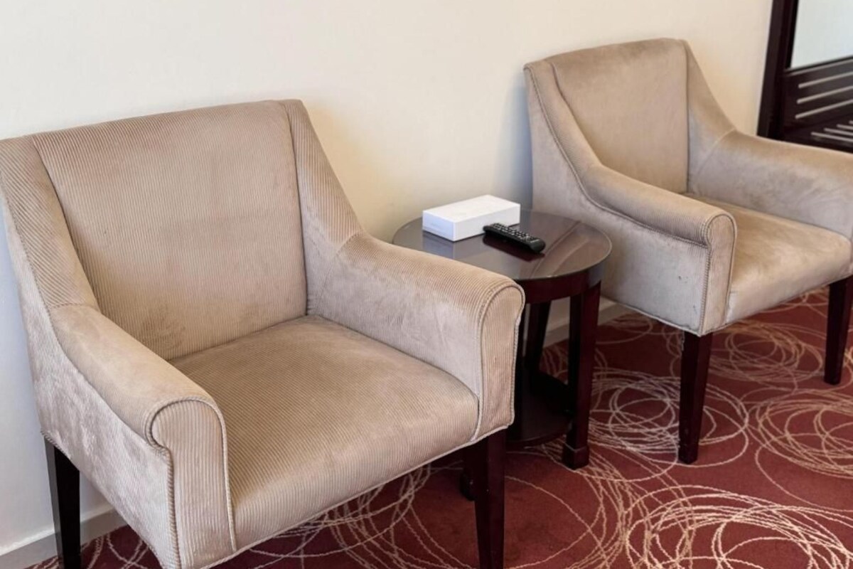 Two armchairs with a remote control on a small table beside them.