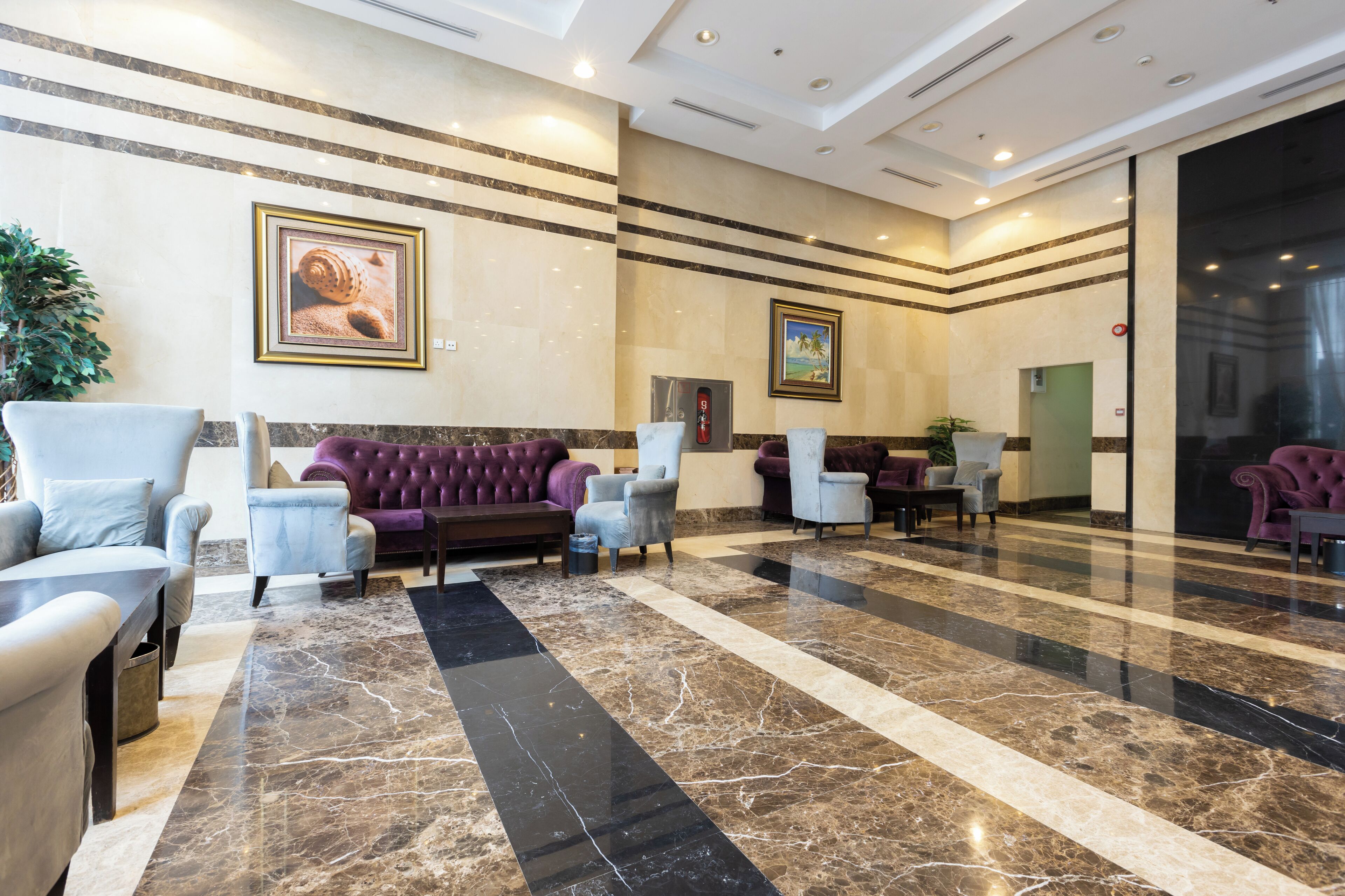 A lobby with a marble floor, seating areas, and framed artwork on the walls.