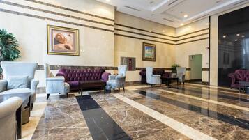 A lobby with a marble floor, seating areas, and framed artwork on the walls.