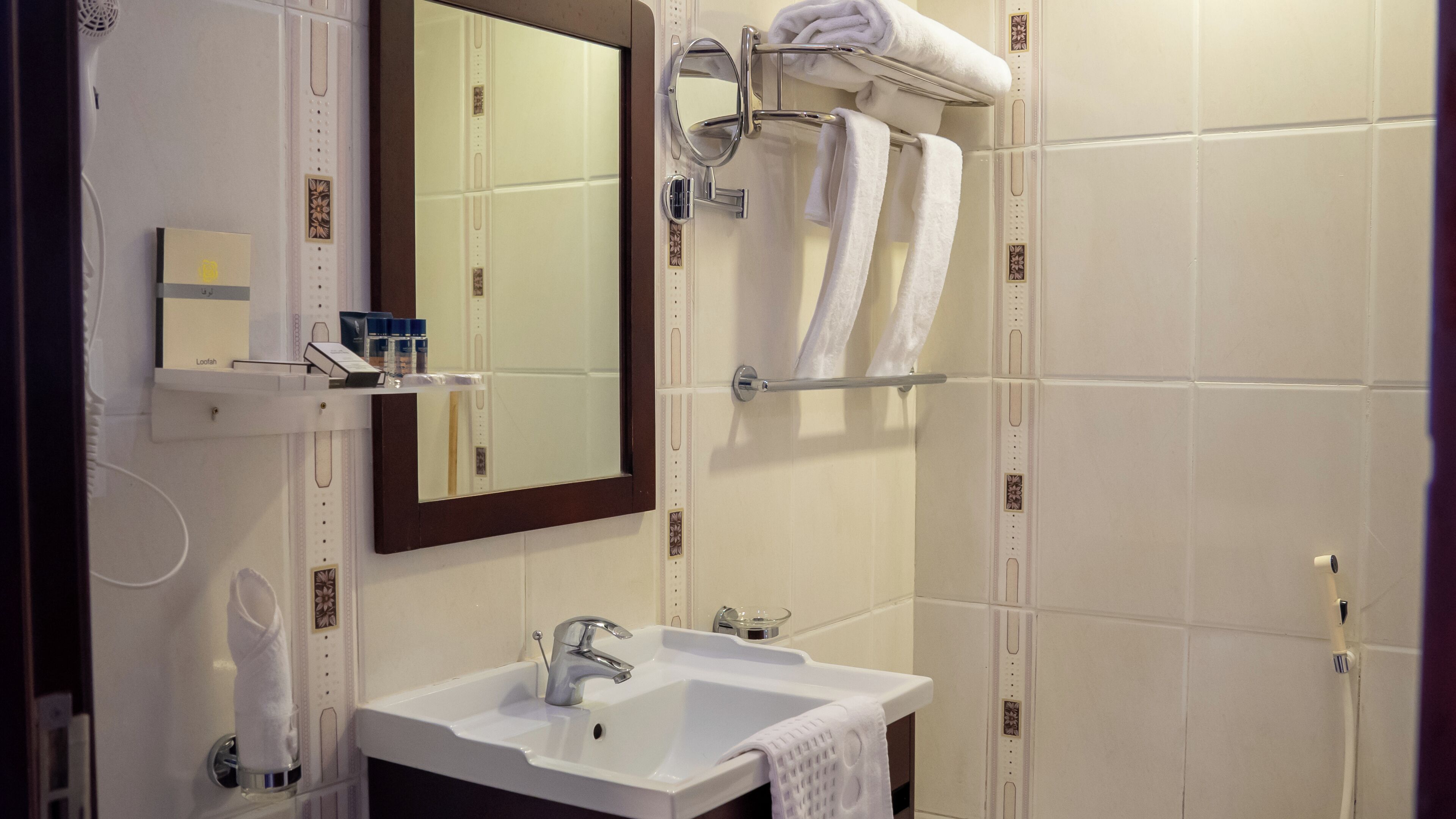 A bathroom with a white sink, mirror, and towel rack.