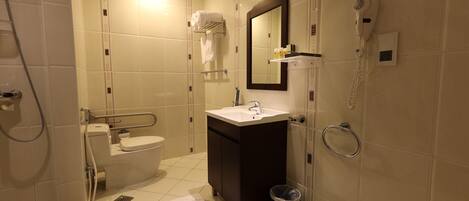 A modern bathroom with a toilet, sink, mirror, and shower.
