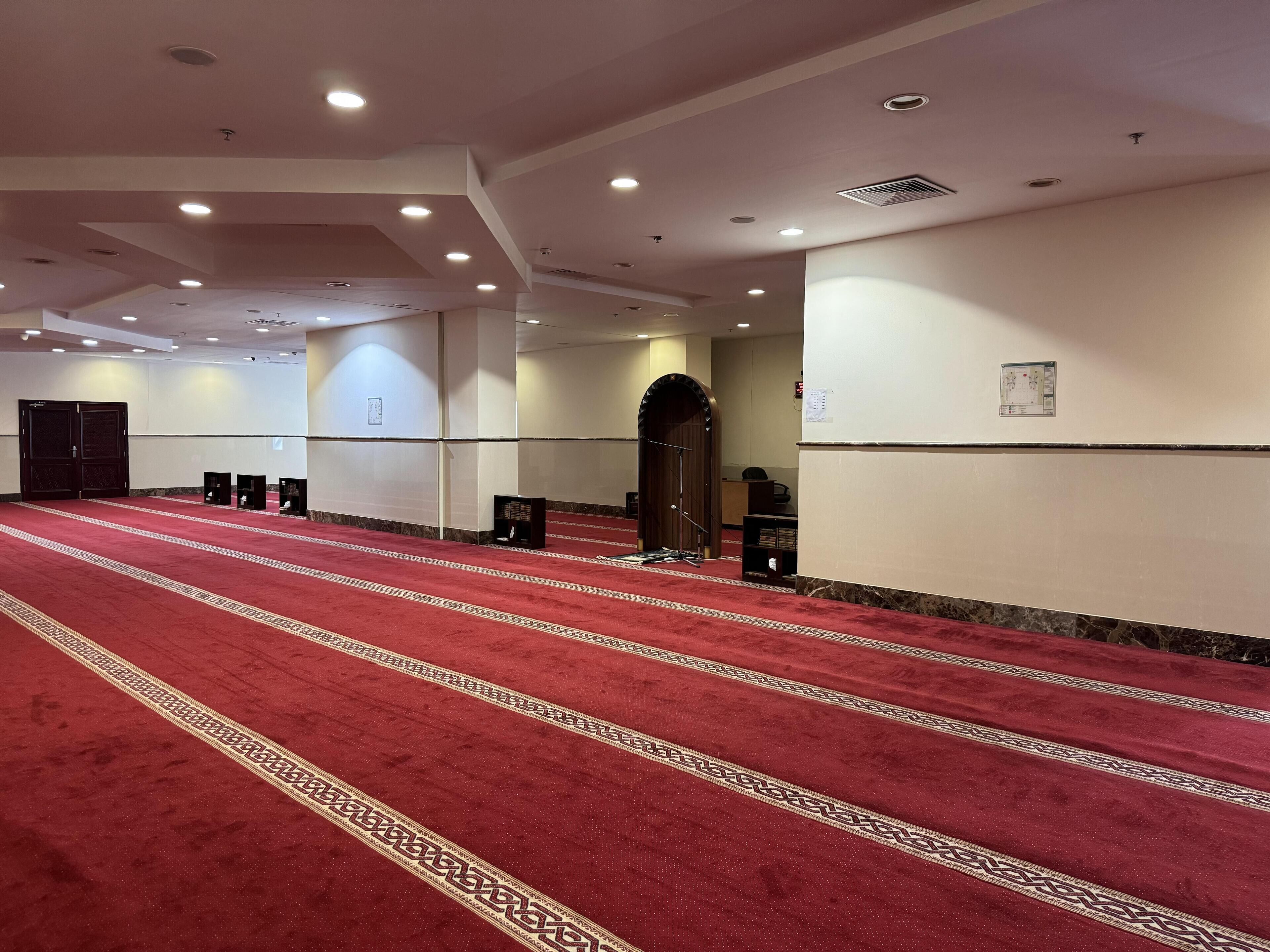Un vaste hall doté d’un tapis rouge, de nombreuses portes et d’une grande entrée en arc de cercle.