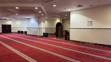 Un vaste hall doté d’un tapis rouge, de nombreuses portes et d’une grande entrée en arc de cercle.