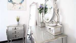 A vintage-style vanity with a large ornate mirror, a small vase with flowers, and a decorative box. - Cosy Cottage with log burner, in the hart of the Norfolk countryside (Buxton)