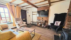 A cozy living room with a fireplace, a television, and a comfortable seating area. - Cosy Cottage with log burner, in the hart of the Norfolk countryside (Buxton)